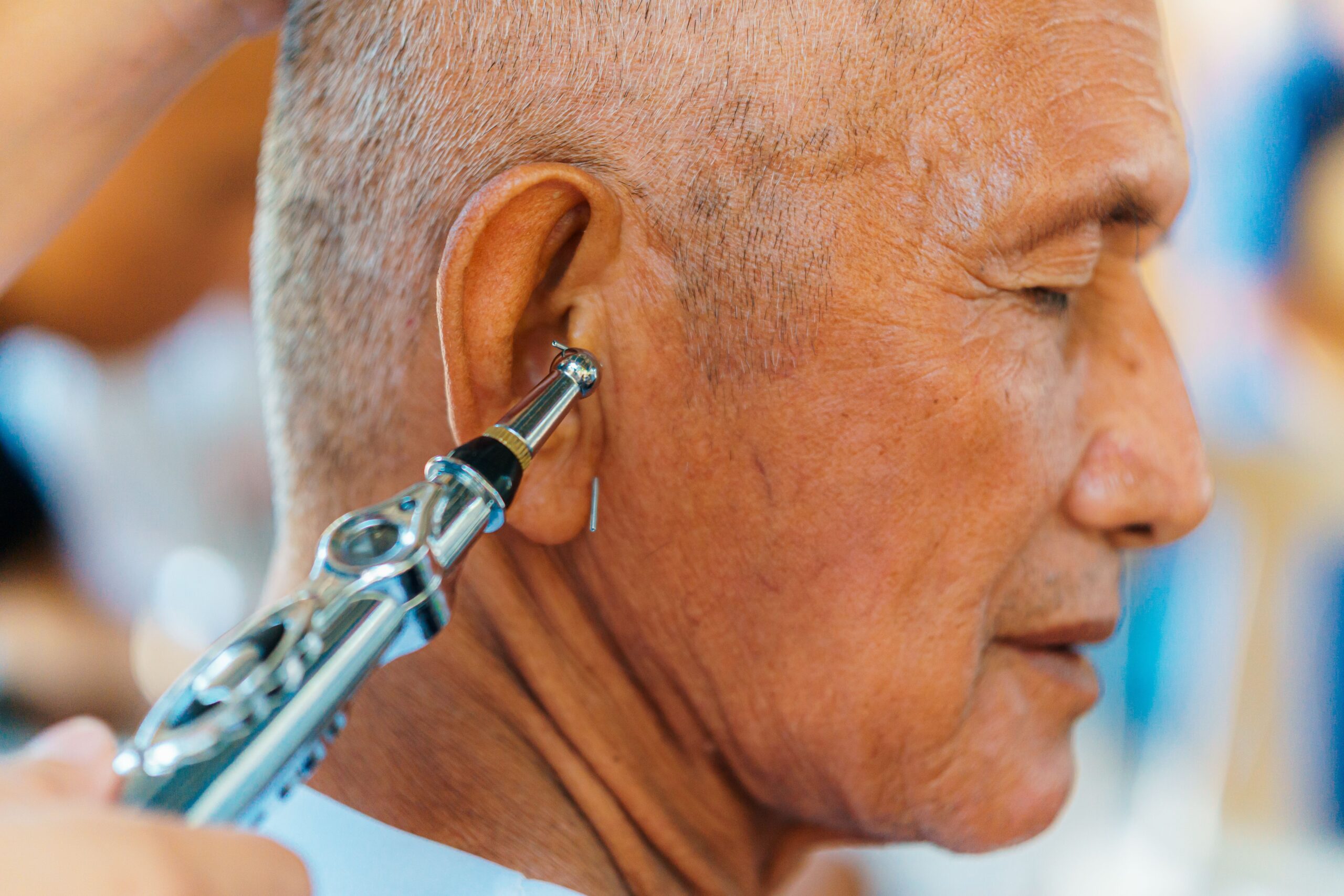 Close-up of a man’s ear during a medical ear examination using an otoscope.